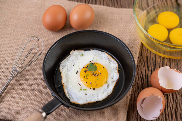 Жареные яйца в сковороде и сырые яйца, органические продукты для хорошего здоровья, высокий уровень белка - Фото, изображение