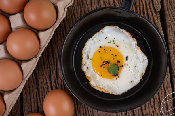Ovos fritos em uma frigideira e ovos crus, alimentos orgânicos para uma boa saúde, ricos em proteínas
 - Foto, Imagem