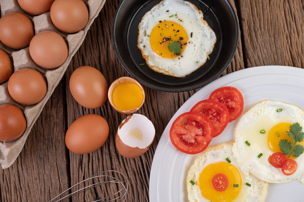 Жареные яйца в сковороде и сырые яйца, органические продукты для хорошего здоровья, высокий уровень белка. - Фото, изображение