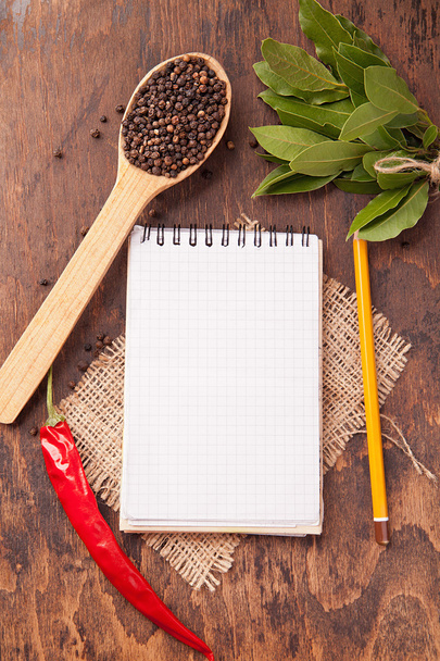 Spices in spoons, notebook on wood background - Fotó, kép