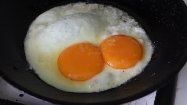 Hot fried egg preparation on old cast frirying pan for breakfast - Záběry, video