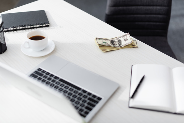Вибірковий фокус доларів біля ноутбука, блокнотів і чашки кави на столі, заробляючи онлайн-концепцію
 - Фото, зображення