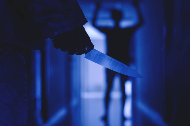 Großaufnahme von Hand mit Messer folgt einem jungen verängstigten Mann, Bandit hält ein Messer in der Hand. Bedrohungskonzept - Foto, Bild