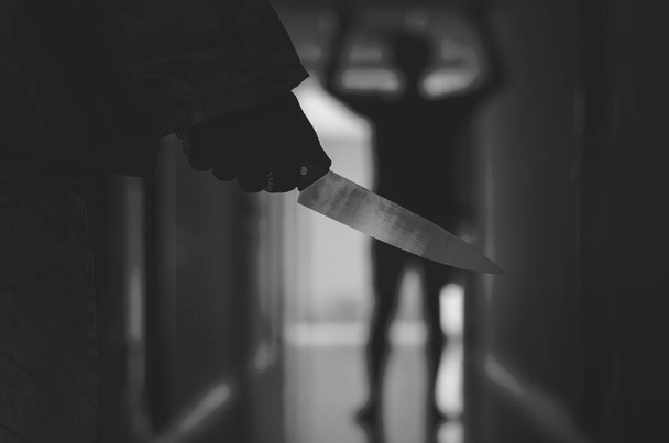 Großaufnahme von Hand mit Messer folgt einem jungen verängstigten Mann, Bandit hält ein Messer in der Hand. Bedrohungskonzept - Foto, Bild