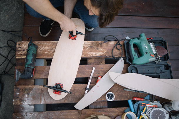 Top view of brunette man assembling skateboard parts - 写真・画像