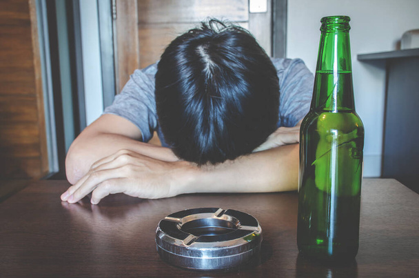 孤独で絶望的なアルコール中毒の男がテーブルで寝てる。アルコール、選択的フォーカスボトルとのトラブルを持つ悲しい落ち込んで男性大人 - 写真・画像