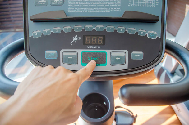 Επιλεκτική εστίαση "έναρξη", Αρσενικό χέρι πιέζει πράσινο κουμπί εκκίνησης σε έναν πίνακα ελέγχου του κλωστηρίου στο γυμναστήριο - Φωτογραφία, εικόνα
