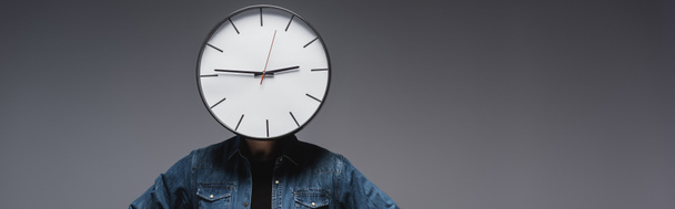 Πανοραμική λήψη του ανθρώπου με το ρολόι στο κεφάλι σε γκρι φόντο, έννοια της διαχείρισης του χρόνου  - Φωτογραφία, εικόνα