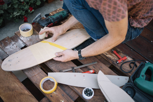 Male hands sticking tape to skateboard deck - Photo, image