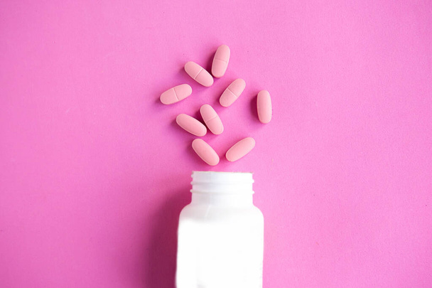 Pillole in bottiglia su sfondo rosa, vista dall'alto - Foto, immagini