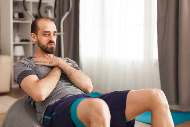Αθλητικός άνθρωπος κάνει ασκήσεις κοιλιακών σε ελβετική μπάλα - Φωτογραφία, εικόνα
