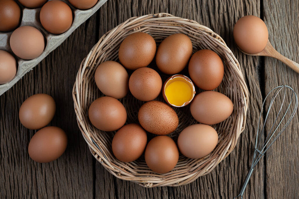 Pon los huevos en una canasta de madera sobre un suelo de madera. Vista superior
. - Foto, Imagen