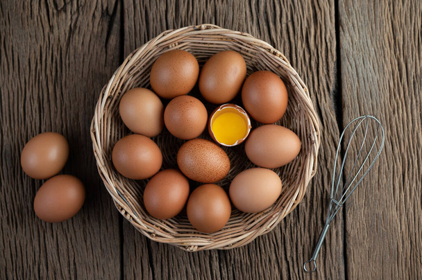 Legen Sie Eier in einen Holzkorb auf einem Holzboden. Ansicht von oben. - Foto, Bild