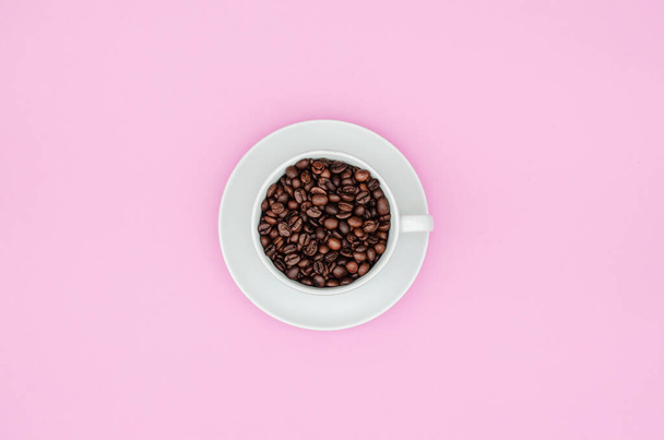 Filiżanka pełna ziaren kawy na różowym pastelowym tle. Przestrzeń kopiowania - Zdjęcie, obraz