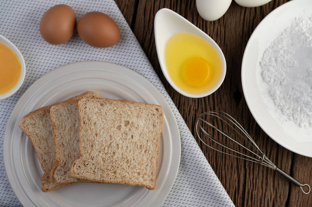 Eggs, bread, tapioca flour and an egg beater, ingredients used in bakery - Photo, Image