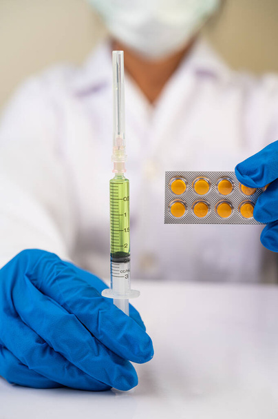 Tiedemiehet naamioissa ja käsineissä Ruiskun pitäminen rokotteella kovic-19:n estämiseksi - Valokuva, kuva