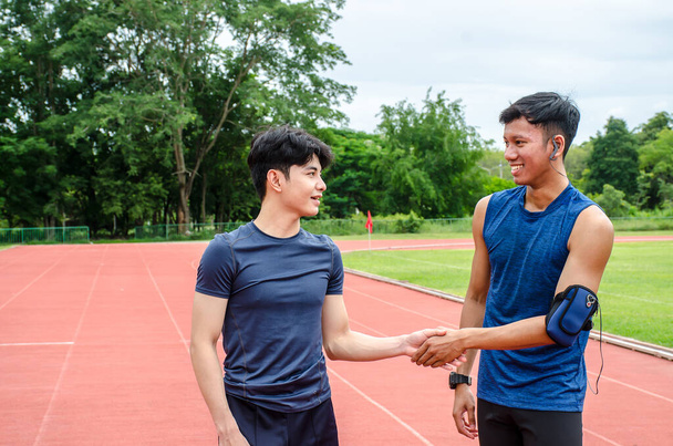 Deux athlètes masculins se serrent la main pour encourager et créer une bonne amitié. Avant de sortir courir dans le stade. espace de copie. - Photo, image