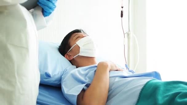 Az orvos gondoskodik egy beteg betegről, aki a kórházi ágyon köhög a koronavírusról. beteg ember egy kórházi ágyon. - Felvétel, videó