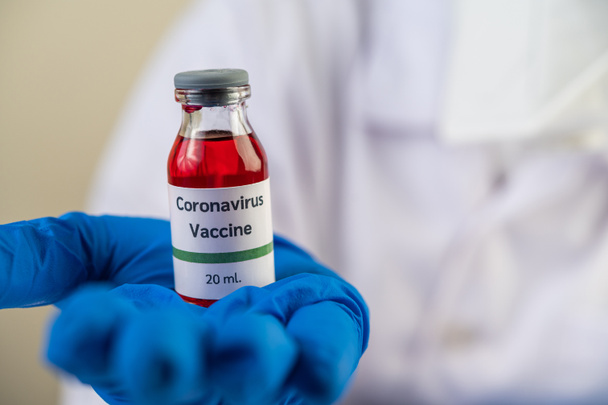 Tiedemiehet naamioituneina ja käsineissä, mukanaan rokotepulloja Covid-19:n suojaamiseksi - Valokuva, kuva