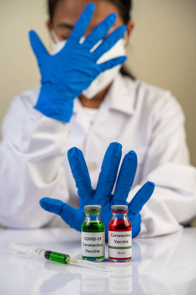 Wissenschaftler tragen blaue Handschuhe und machen Hände zu unannehmbaren Impfstoffen - Foto, Bild