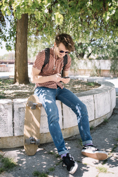 Joyful guy chatting online via cellphone in park - Valokuva, kuva