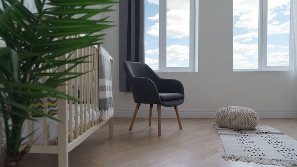 Moderne grijze stoel en kruk bladerdeeg op geweven tapijt in kinderkamer - Foto, afbeelding