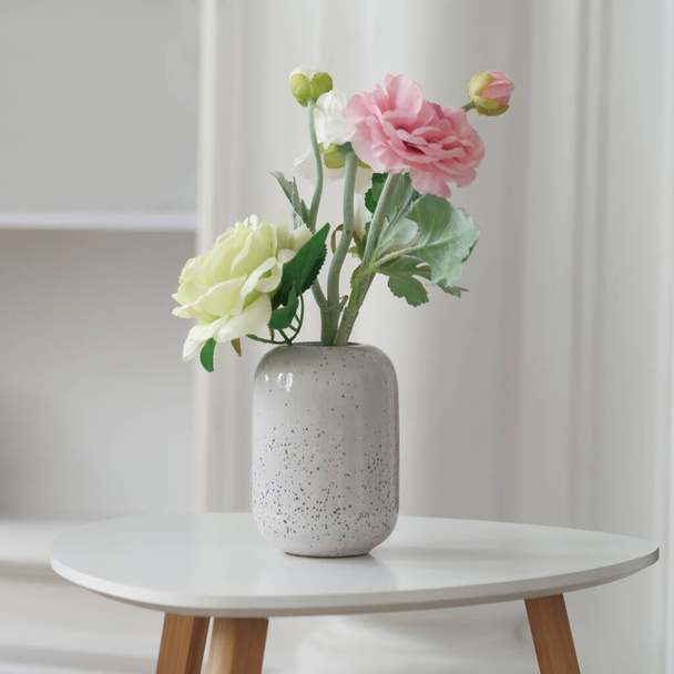 Розовые и желтые розы в современной белой вазе на белом столе
 - Фото, изображение