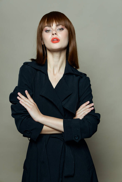 Sexy woman with red lips and in a black coat on isolated background - Valokuva, kuva