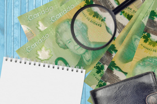 20 Канадські доларові банкноти та збільшуюче скло з чорною сумочкою та блокнотом. Концепція підроблених грошей. Шукайте відмінності в деталях на грошових рахунках, щоб виявити фальшиві гроші. - Фото, зображення