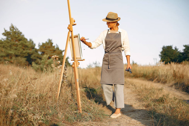 Woman in a apron painting in a field - Foto, Imagen