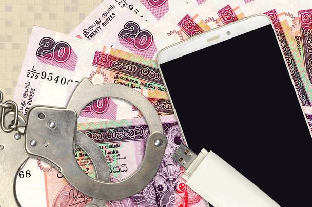 20 Sri Lankan rupees bills and smartphone with police handcuffs. Concept of hackers phishing attacks, illegal scam or online spyware soft distribution - Photo, Image