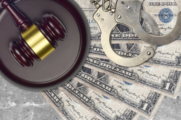 1ドル札と裁判所の机の上に警察の手錠でハンマーを判断します。裁判や贈賄の概念。脱税又は脱税 - 写真・画像