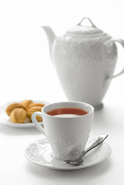 Крупним планом вид на десертну тарілку, чайник і чашки на білому тлі
 - Фото, зображення