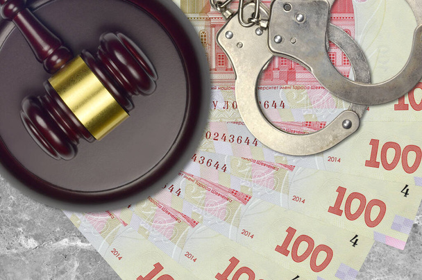 100ウクライナのフリヴニア法案と裁判所の机の上に警察の手錠でハンマーを判断します。裁判や贈賄の概念。脱税又は脱税 - 写真・画像