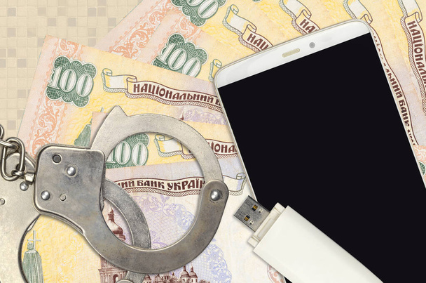 100 Ukrainian hryvnias bills and smartphone with police handcuffs. Concept of hackers phishing attacks, illegal scam or online spyware soft distribution - Photo, Image