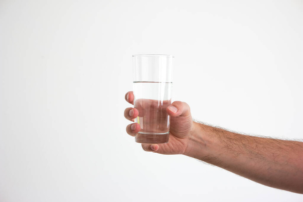 Caucasian adult male hand holding a clear glass of water isolated on white 2020 - Foto, immagini