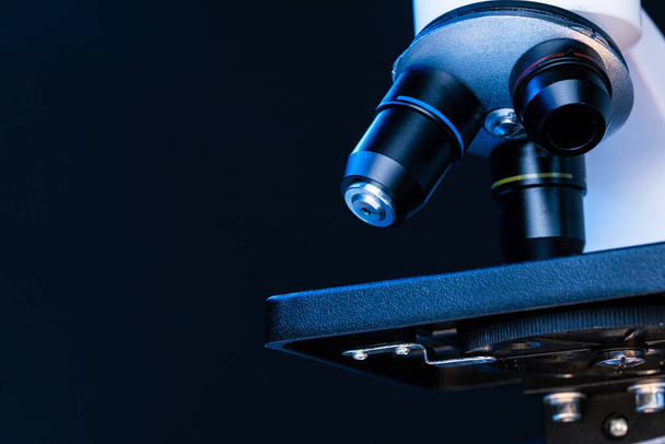 Microscopio con lentes cerca sobre fondo oscuro
 - Foto, imagen