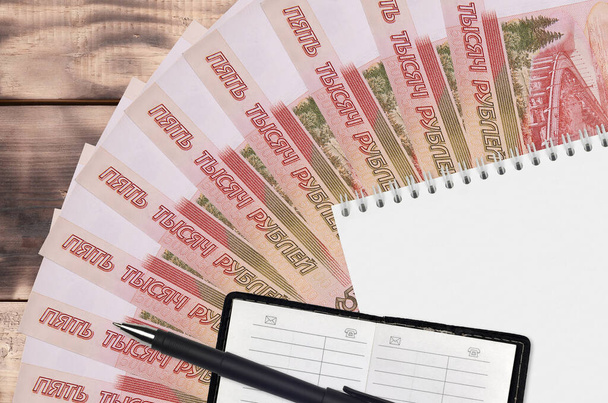 5000 russian rubles bills fan and notepad with contact book and black pen. Concept of financial planning and business strategy. Accounting and investment - Photo, Image