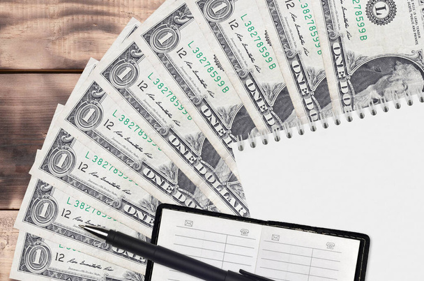 1 amerikai dollár számlák rajongó és jegyzettömb kontakt könyv és fekete toll. A pénzügyi tervezés és az üzleti stratégia koncepciója. Számvitel és befektetés - Fotó, kép