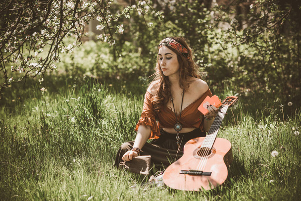 Gypsy woman with Tarot cards and guitar at field, lifestyle, predicting, ideas for costume on Halloween - Photo, Image