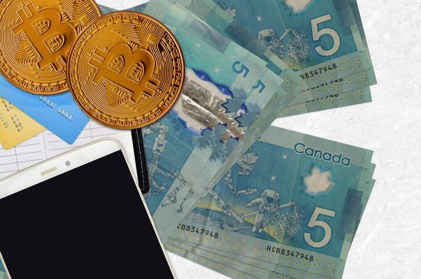 5 billets en dollars canadiens et bitcoins dorés avec smartphone et cartes de crédit. Concept d'investissement crypto-monnaie. Opérations minières ou commerciales cryptographiques - Photo, image