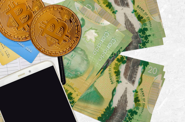 20 kanadyjskich banknotów i złotych bitcoinów ze smartfonem i kartami kredytowymi. Koncepcja inwestycji kryptowaluta. Transakcje wydobywcze lub handlowe kryptograficzne - Zdjęcie, obraz