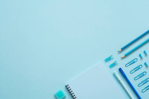 Education concept. Blue stationery set on blue background. Top view of paper pins, notebook, felt-tip pens, eraser, paper clips and pencils. Knolling. Copy space. - Fotó, kép