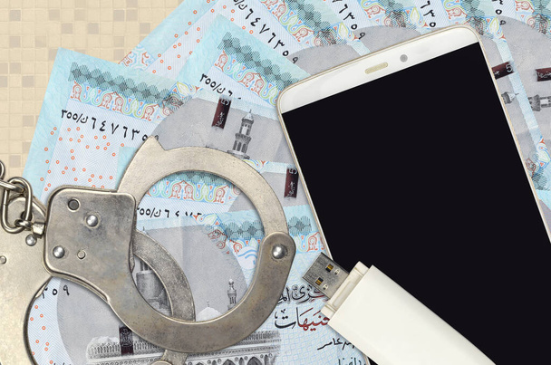 5 Livres égyptiennes factures et smartphone avec menottes de police. Concept de pirates hameçonnage attaques, escroquerie illégale ou la distribution de logiciels espions en ligne - Photo, image