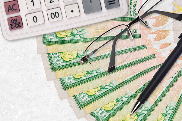 10 Sri Lanki rachunki rupii wentylator i kalkulator z okularami i długopisem. Pożyczka biznesowa lub płatność podatkowa pojęcie sezonu. Planowanie finansowe - Zdjęcie, obraz