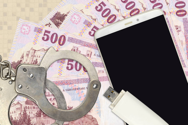 500 Unkarin forintti laskut ja älypuhelin poliisin käsiraudat. Käsitteen hakkerit phishing hyökkäyksiä, laiton huijaus tai online vakoiluohjelmia pehmeä jakelu - Valokuva, kuva