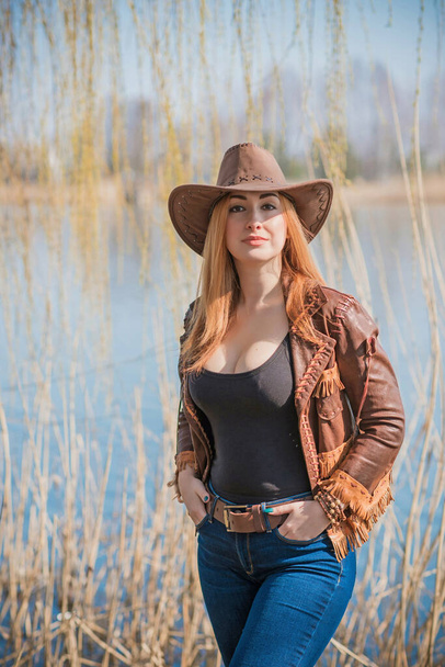Cowgirl style automne américain, femme pleine figure L en veste en cuir, jeans et chapeau - Photo, image