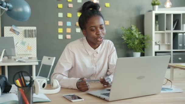 Веселая афро-американка делает онлайн видео-звонок с ноутбуком на рабочем месте
 - Кадры, видео