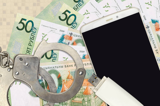50 Belorussian rubles bills and smartphone with police handcuffs. Concept of hackers phishing attacks, illegal scam or online spyware soft distribution - Photo, Image