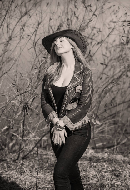 Cowgirl Amerikaanse herfst stijl, full L figuur vrouw in lederen jas, jeans en hoed - Foto, afbeelding